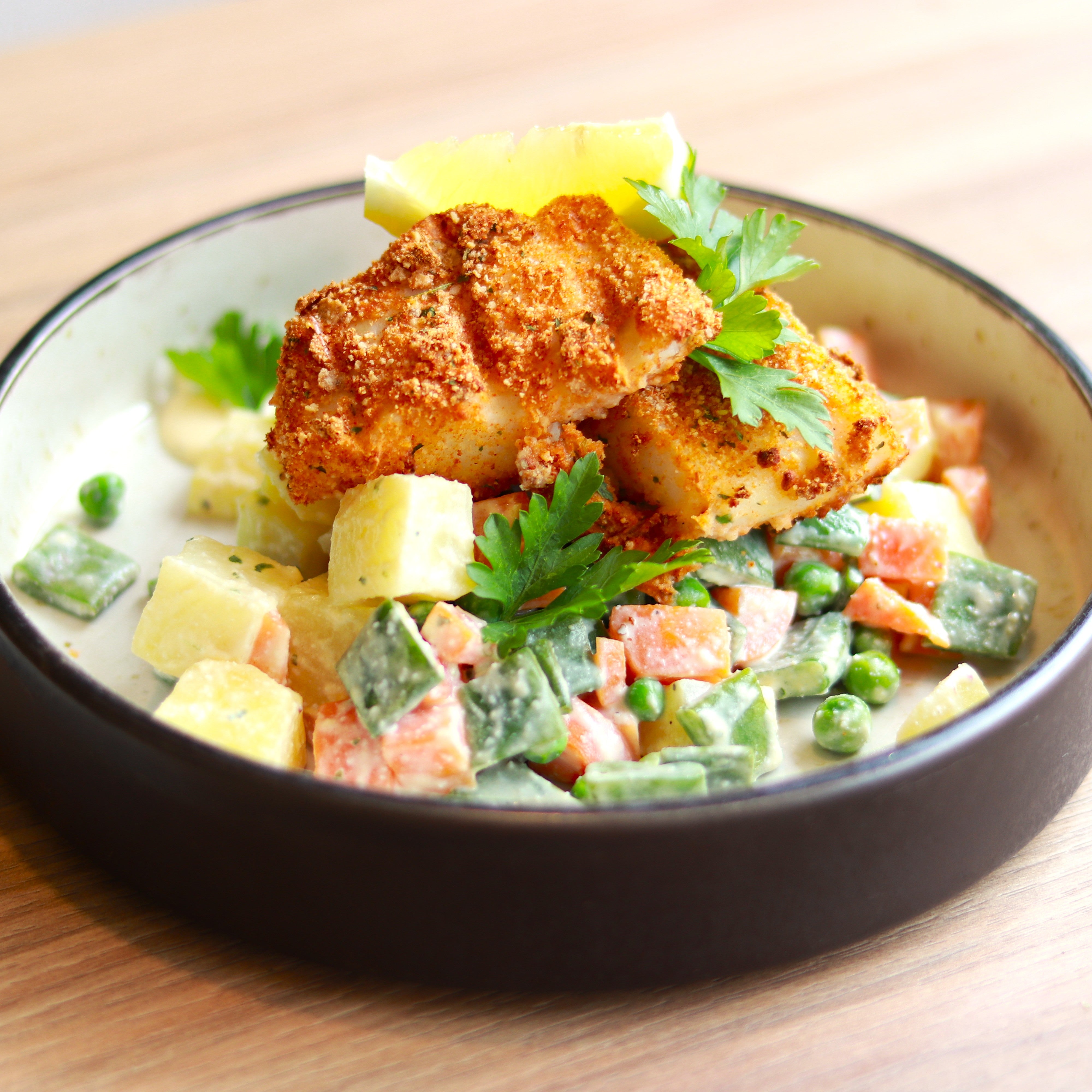 Baked breaded hake fillet with Russian salad